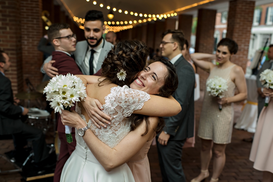 A bride and bridesmaid hug after the ceremony.
